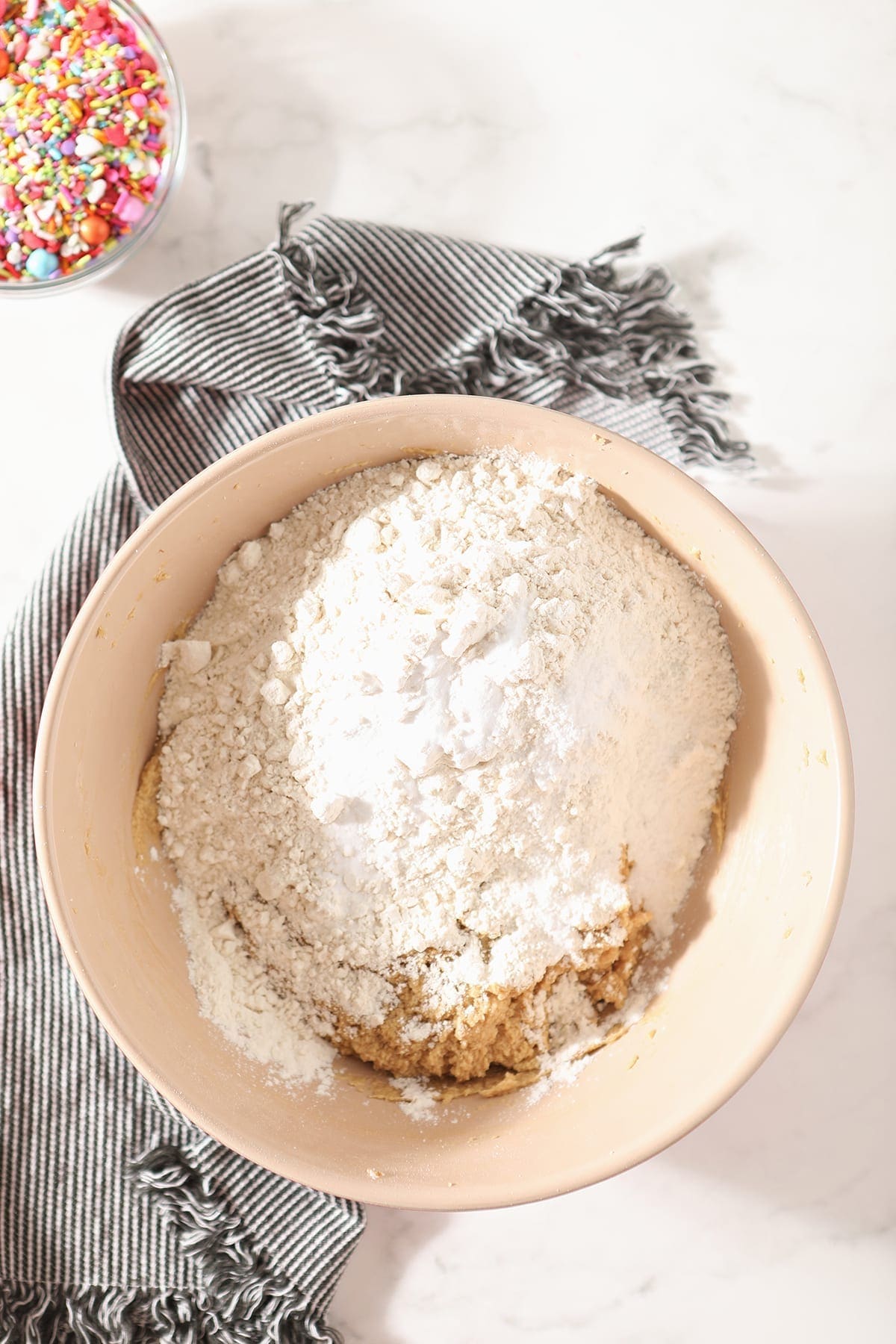 Flour is shown on top of other ingredients in a bowl