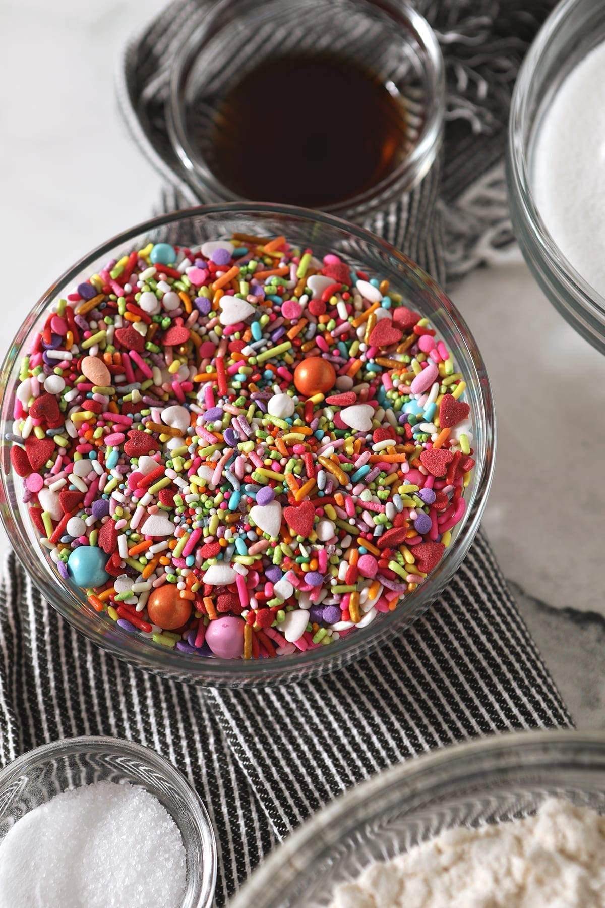 A bowl of colorful sprinkles, surrounded by other ingredients