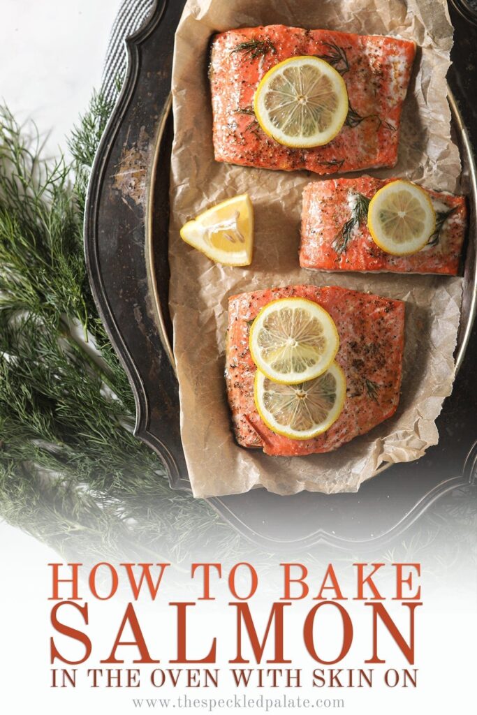 Baked salmon on a silver platter garnished with lemon rounds and surrounded by fresh dill with Pinterest text stating, "How to Bake Salmon in the oven with skin on"