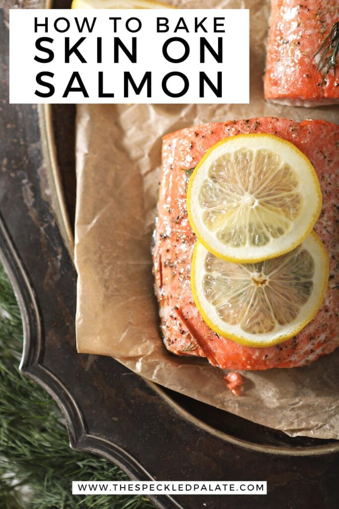 Close up of a baked salmon filet with a lemon round on parchment on a silver platter with Pinterest text stating, "How to bake skin on salmon"