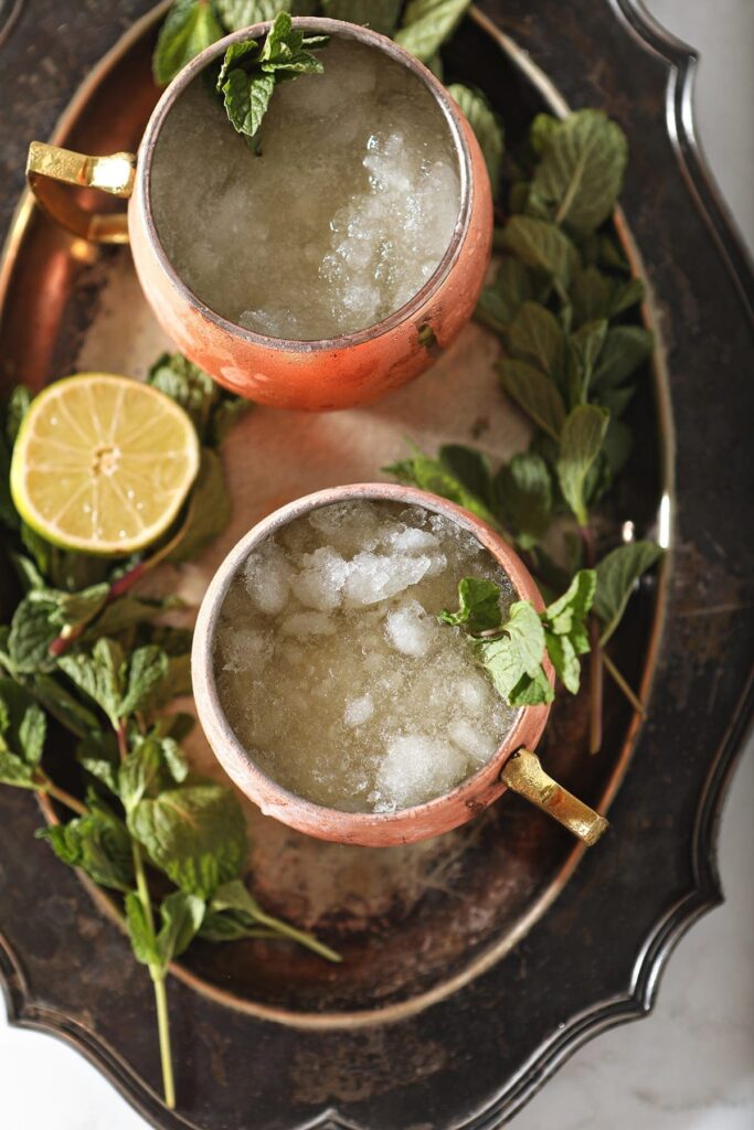 Overhead of a silver platter holding two copper mugs of Kentucky Mules