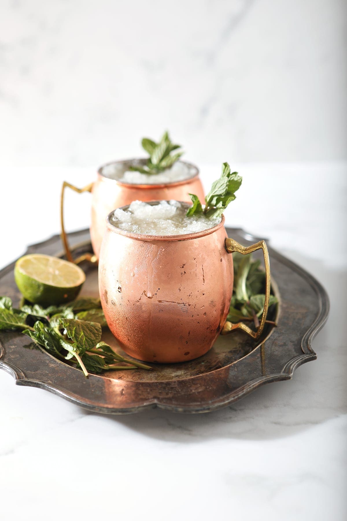 A silver platter holds two copper mugs holding Kentucky Bourbon Mules