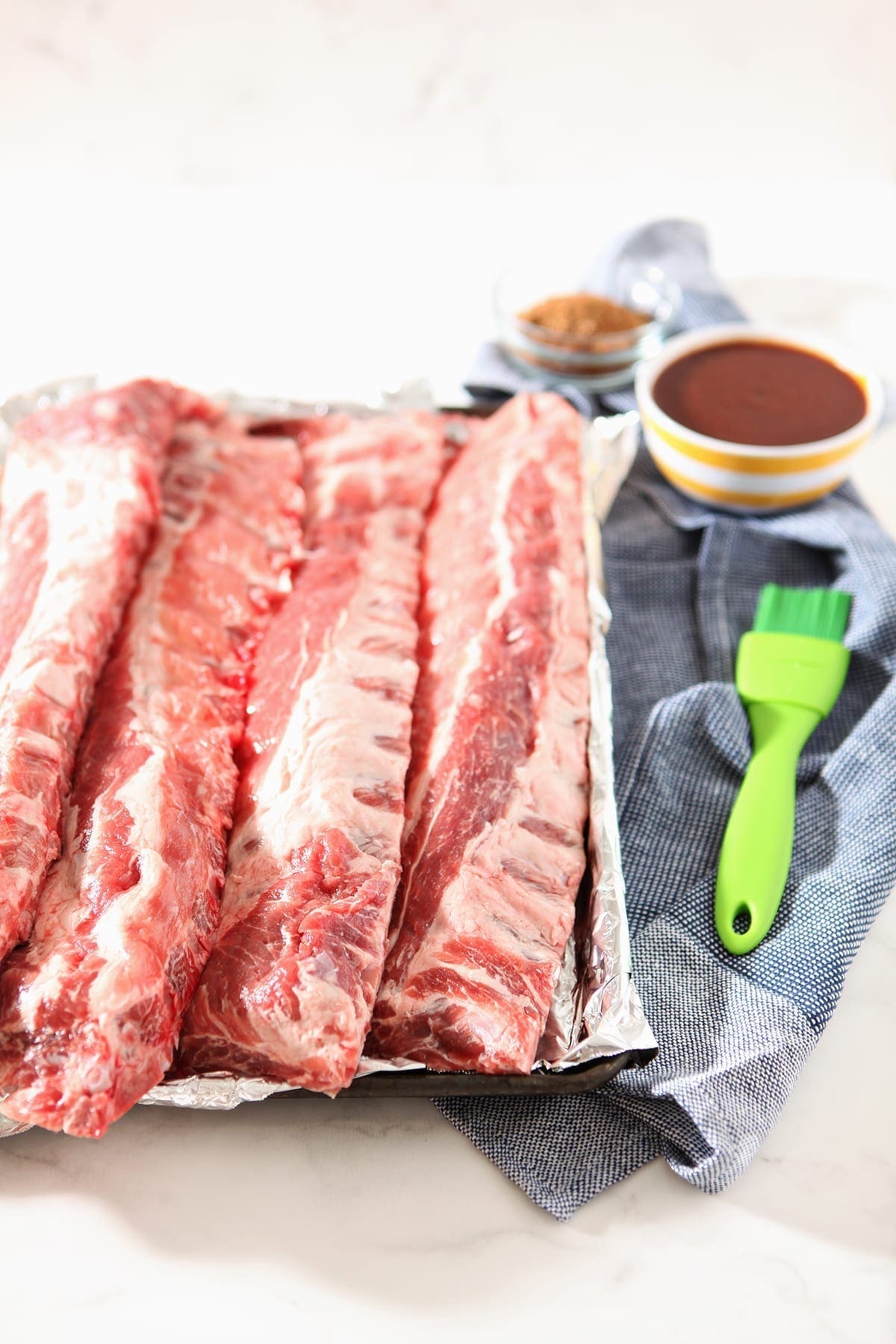 A baking sheet holds pork baby back ribs, before the ribs are baked