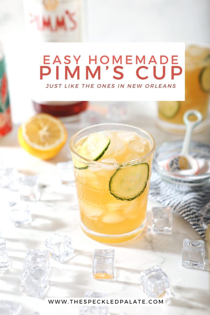 Two Pimm's Cups are surrounded by ingredients and ice, from a 45 degree angle, on marble, with Pinterest text