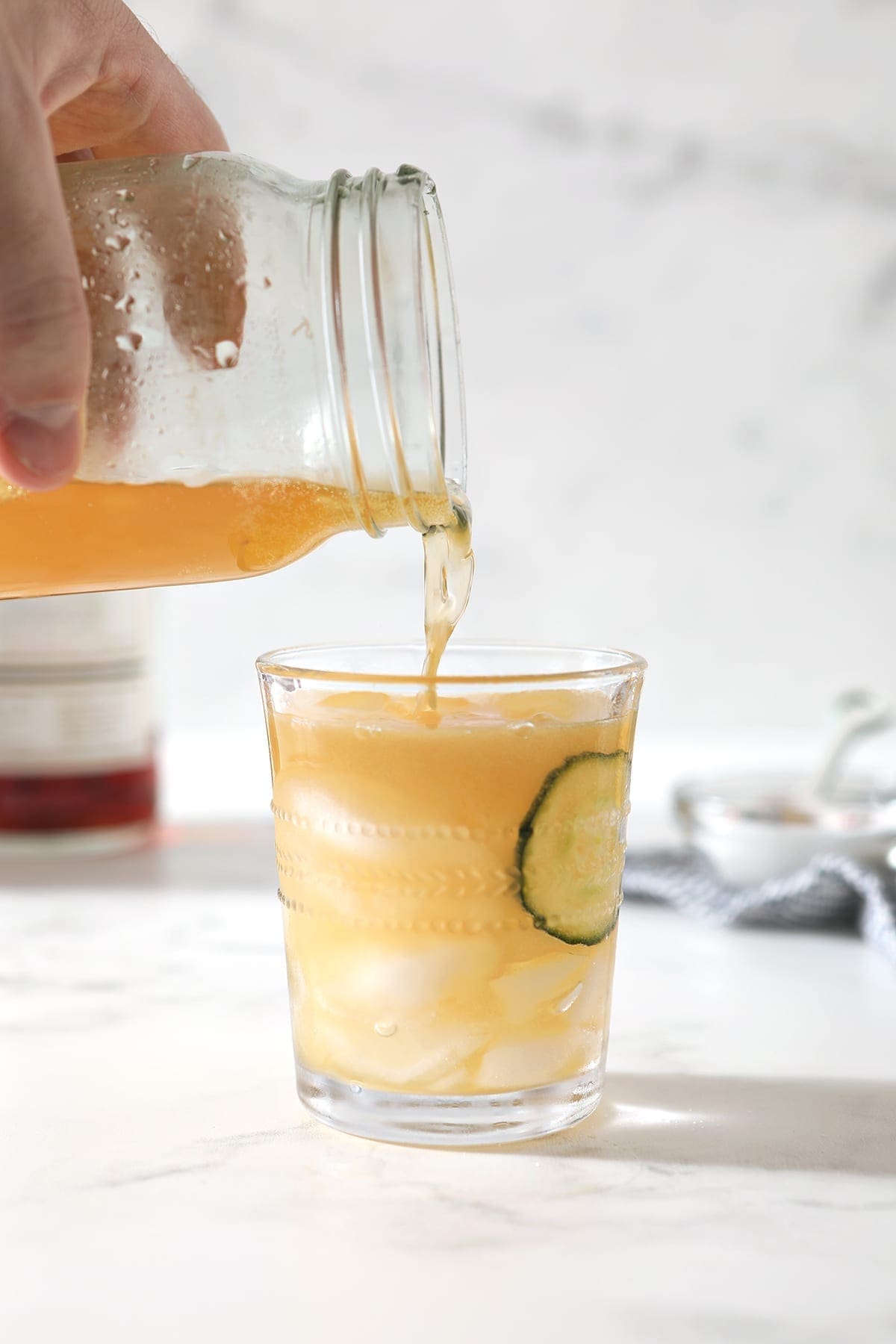 The final cocktail is poured into a glass with ice and cucumbers