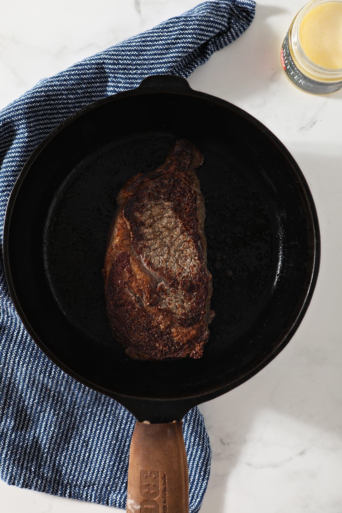 A ribeye, in a cast iron skillet, after flipping