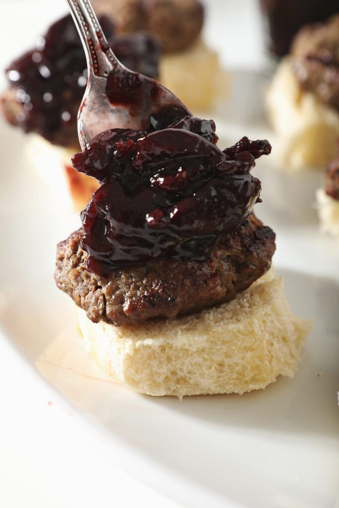 Bacon Cherry Compote is spooned on top of a hamburger slider