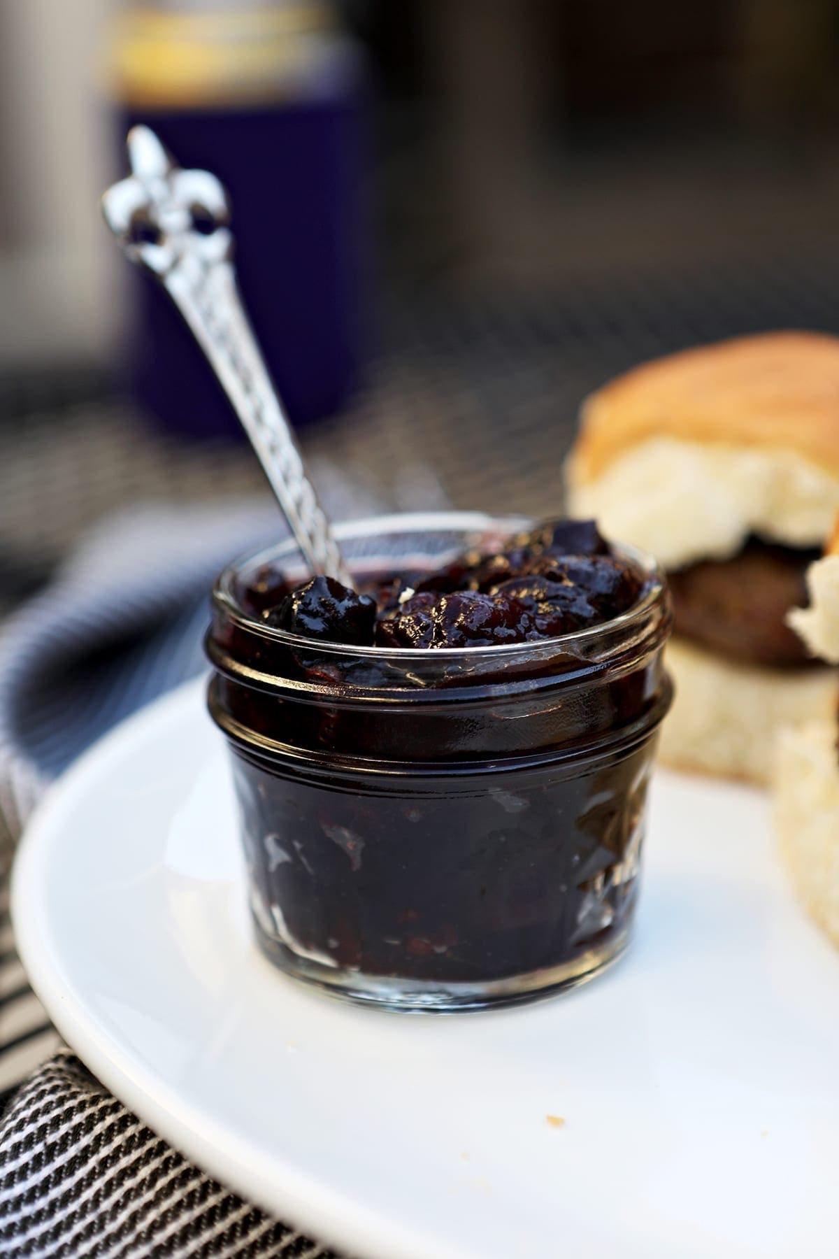 A small jar of compote sits on a white platter next to sliders