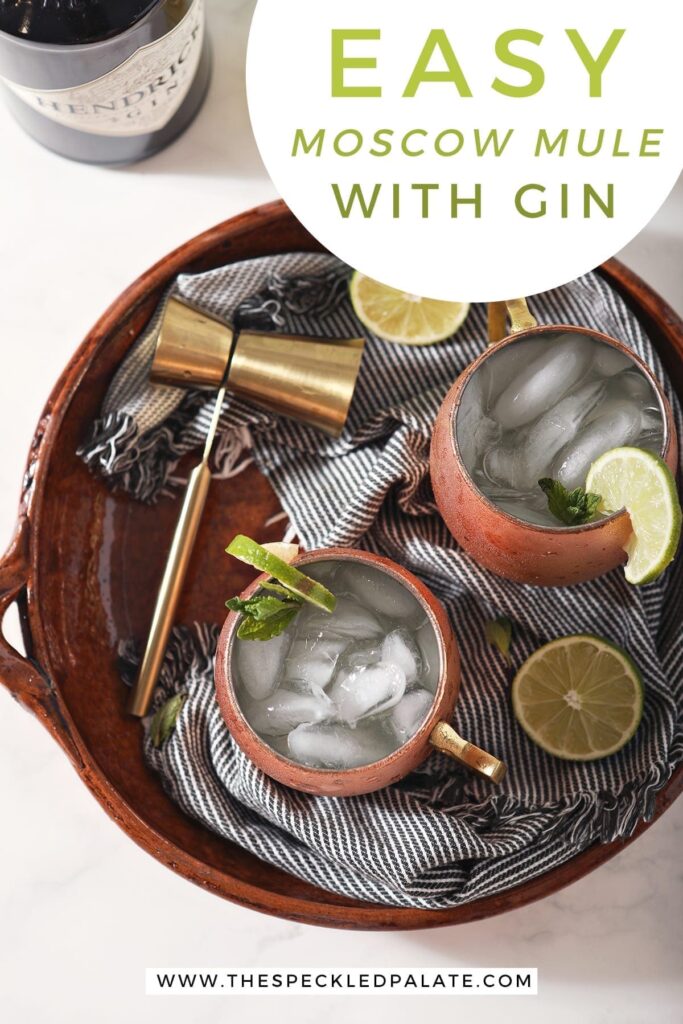 Overhead of two mule mugs holding a Gin Gin Mule on top of a blue striped towel on a brown serving platter with text stating, "How to Make a Moscow Mule with Gin"