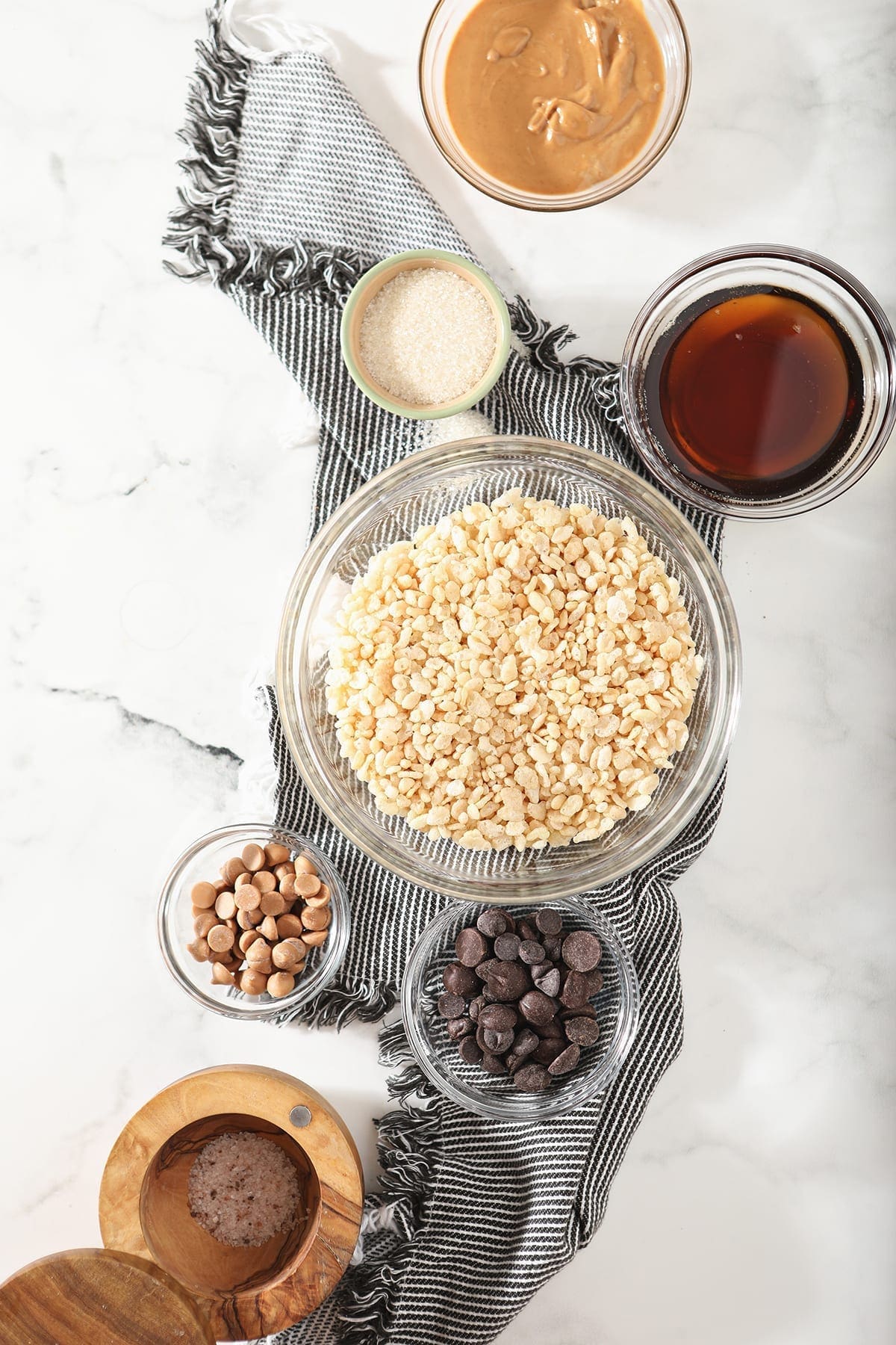 Ingredients for No Bake Peanut Butter Cookies in bowls on a grey and white striped towel on a marble background