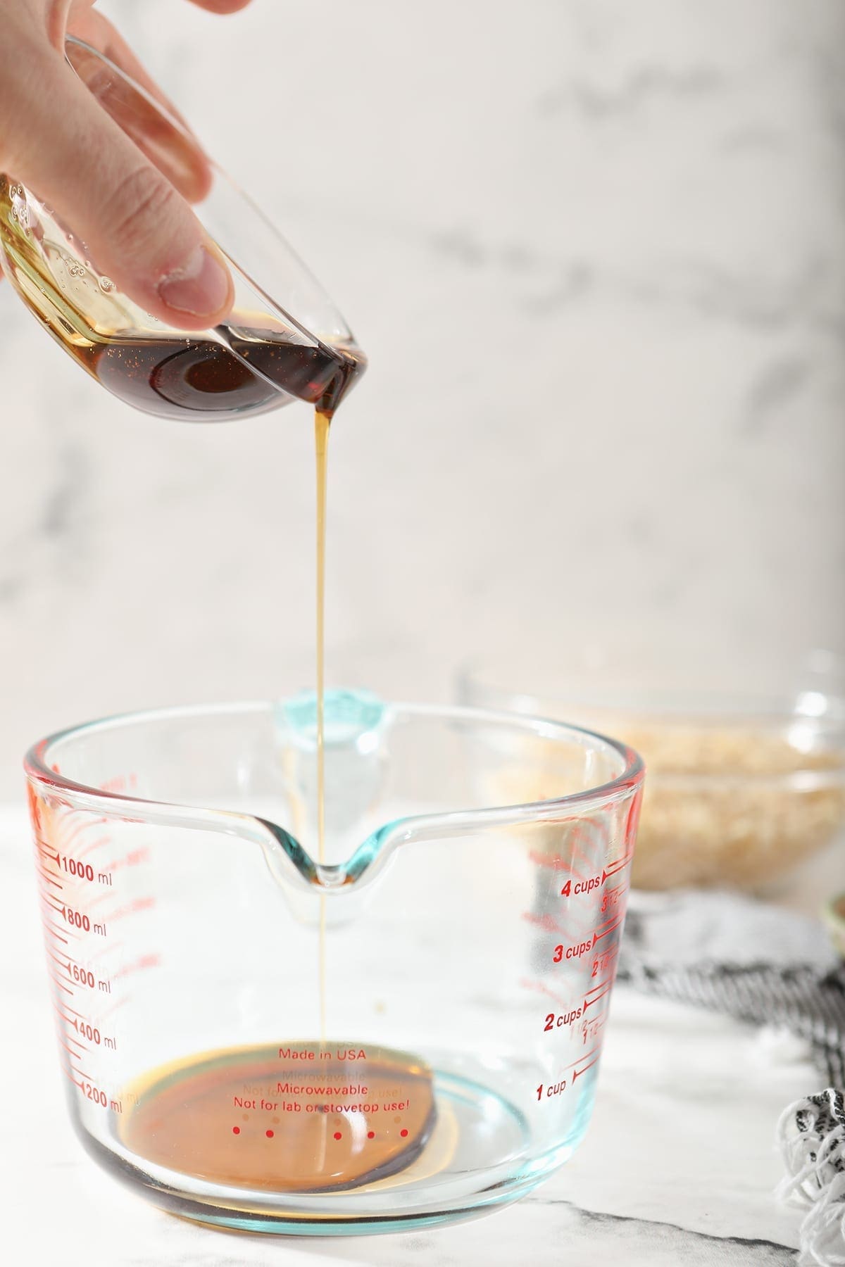 Maple syrup is poured into a clear glass measuring cup