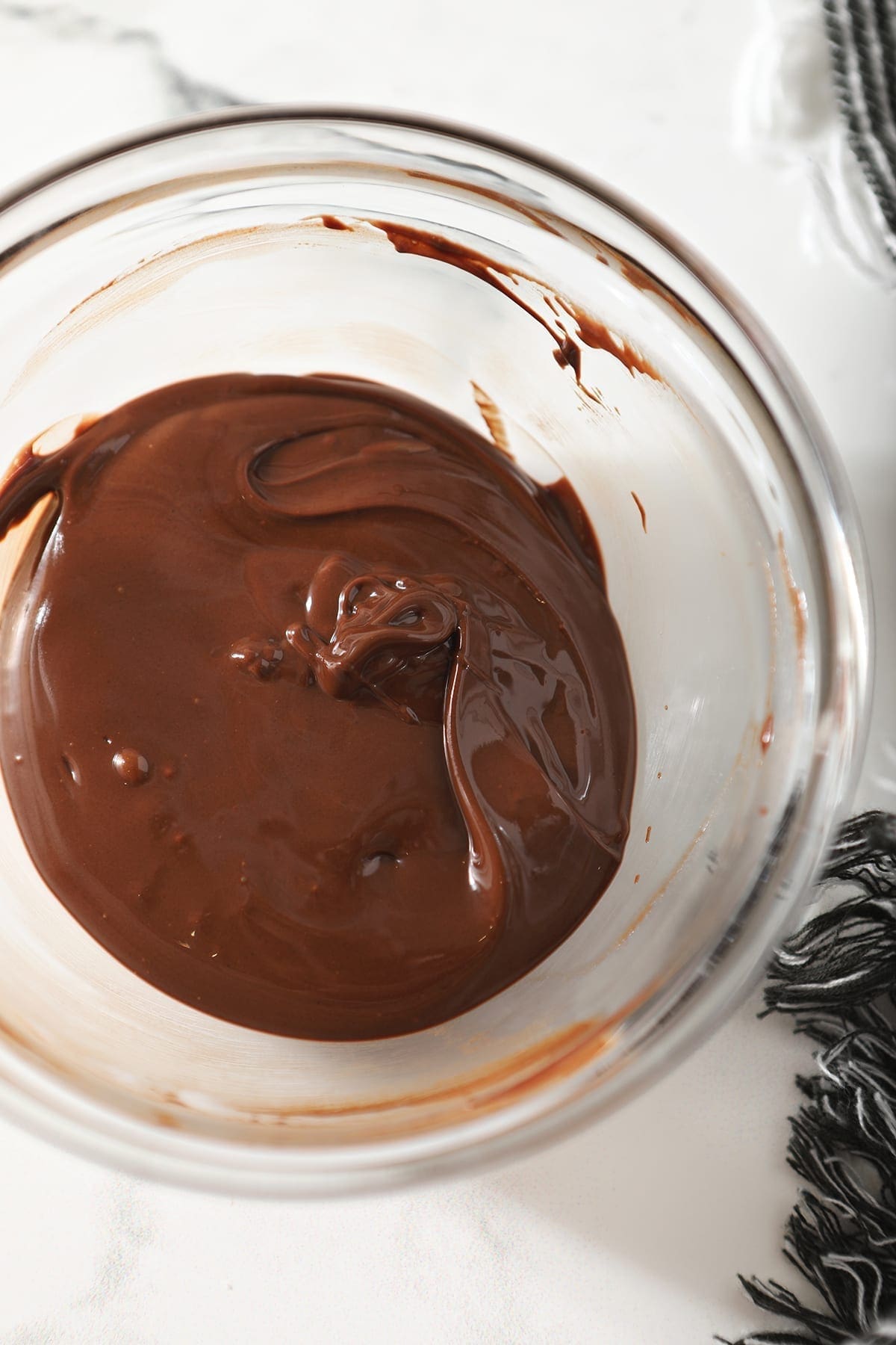 A chocolate-butterscotch mixture in a clear glass bowl on marble