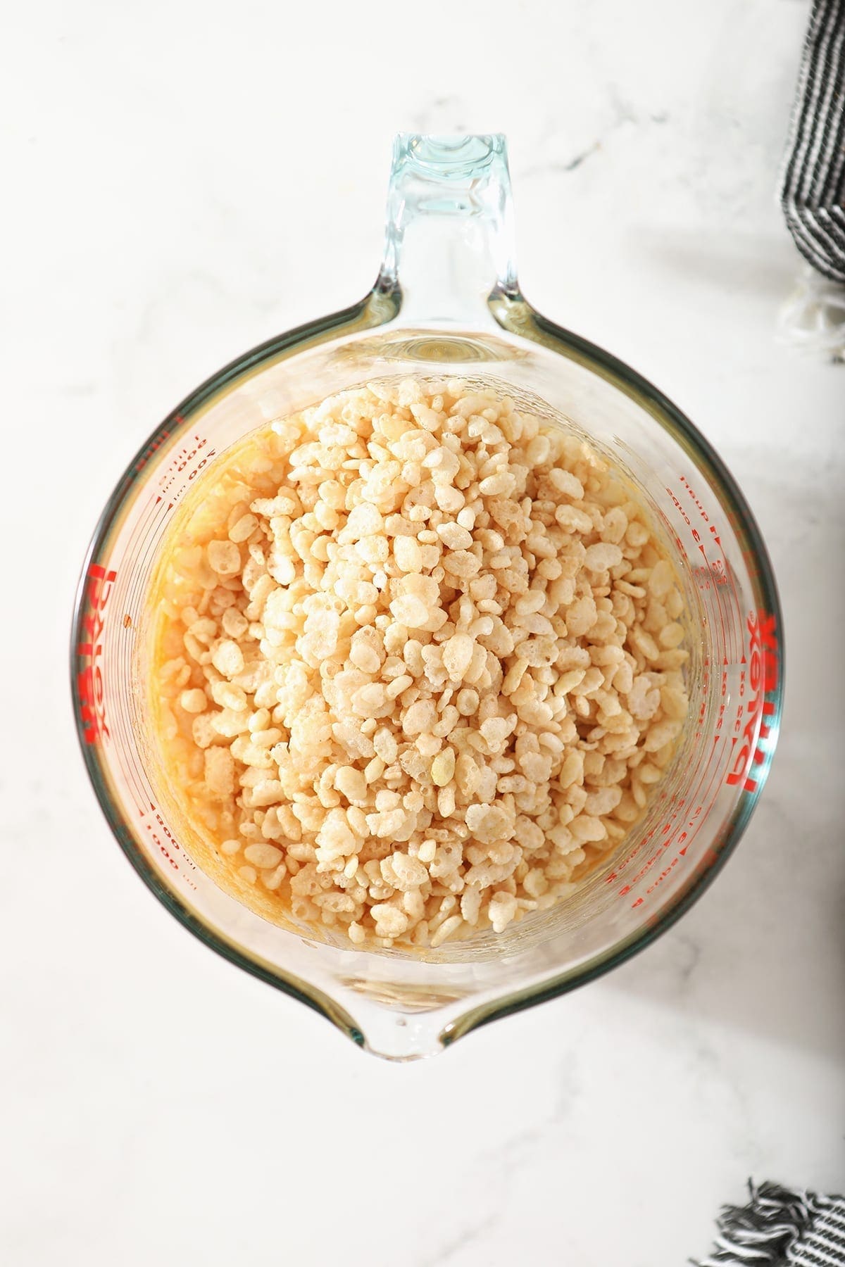 Toasted rice cereal in a liquid measuring cup on top of wet ingredients