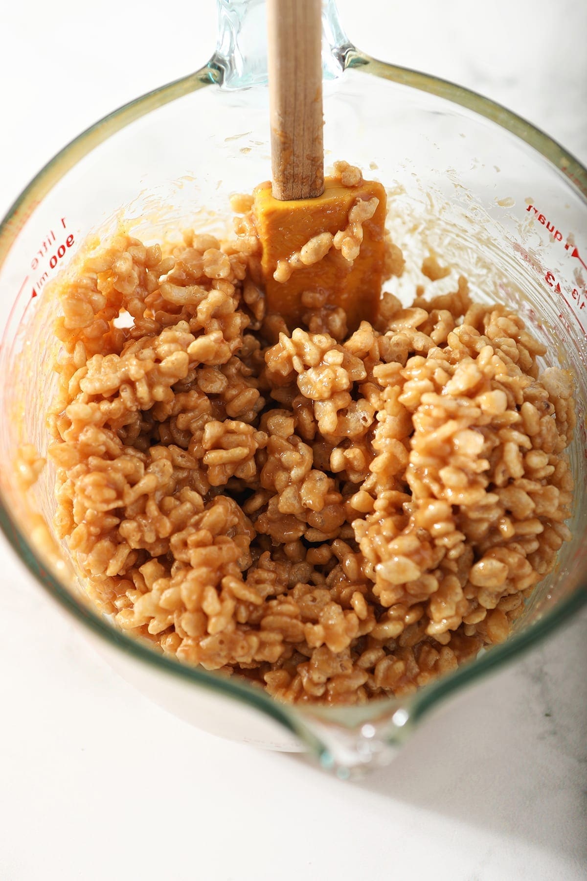 Ingredients for No Bake Peanut Butter Cookies mix together with a yellow rubber spatula in a liquid measuring cup