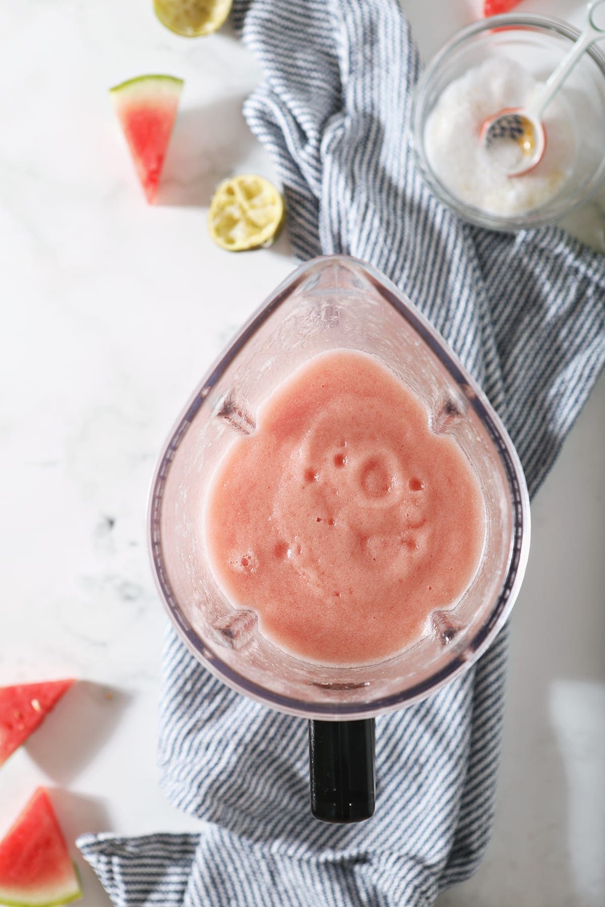 Overhead of a blender on a marble countertop holding a slushy pink mixture