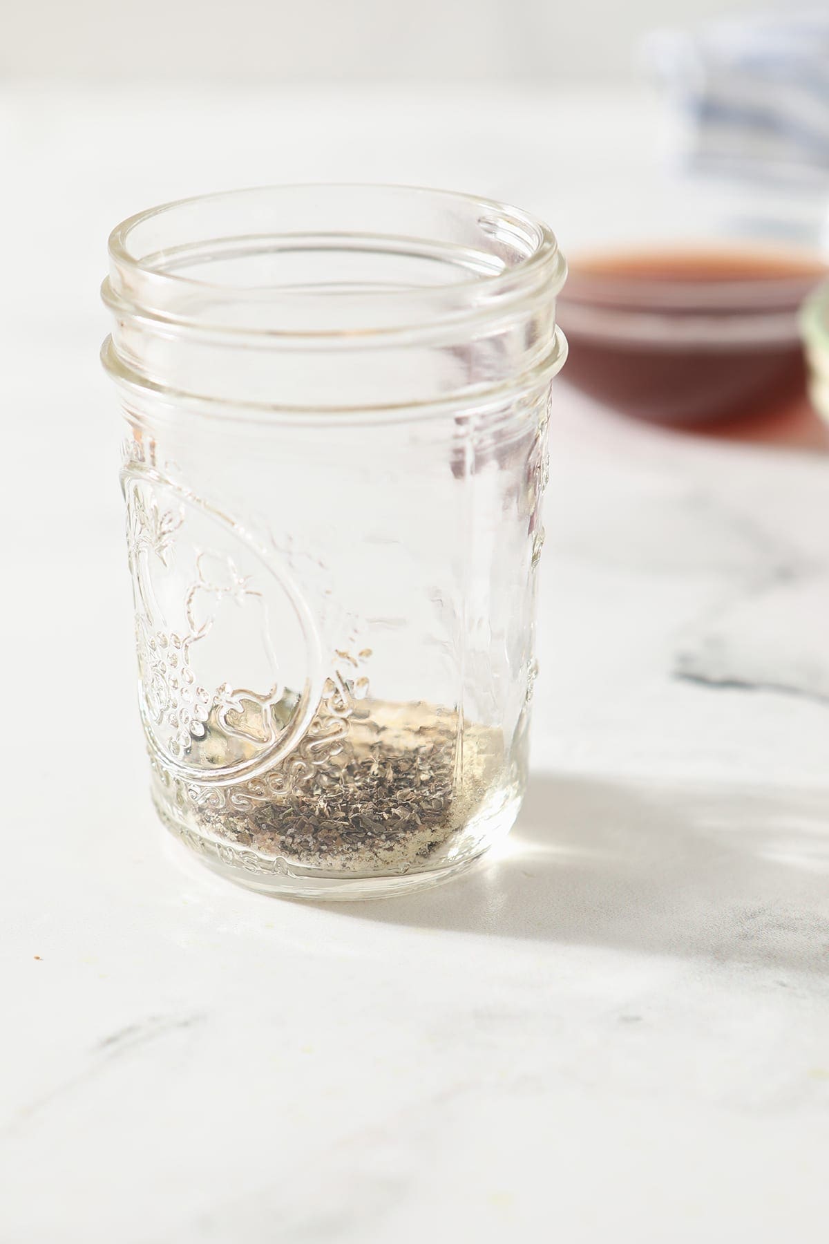 A mason jar holds spices while sitting on a marble surface