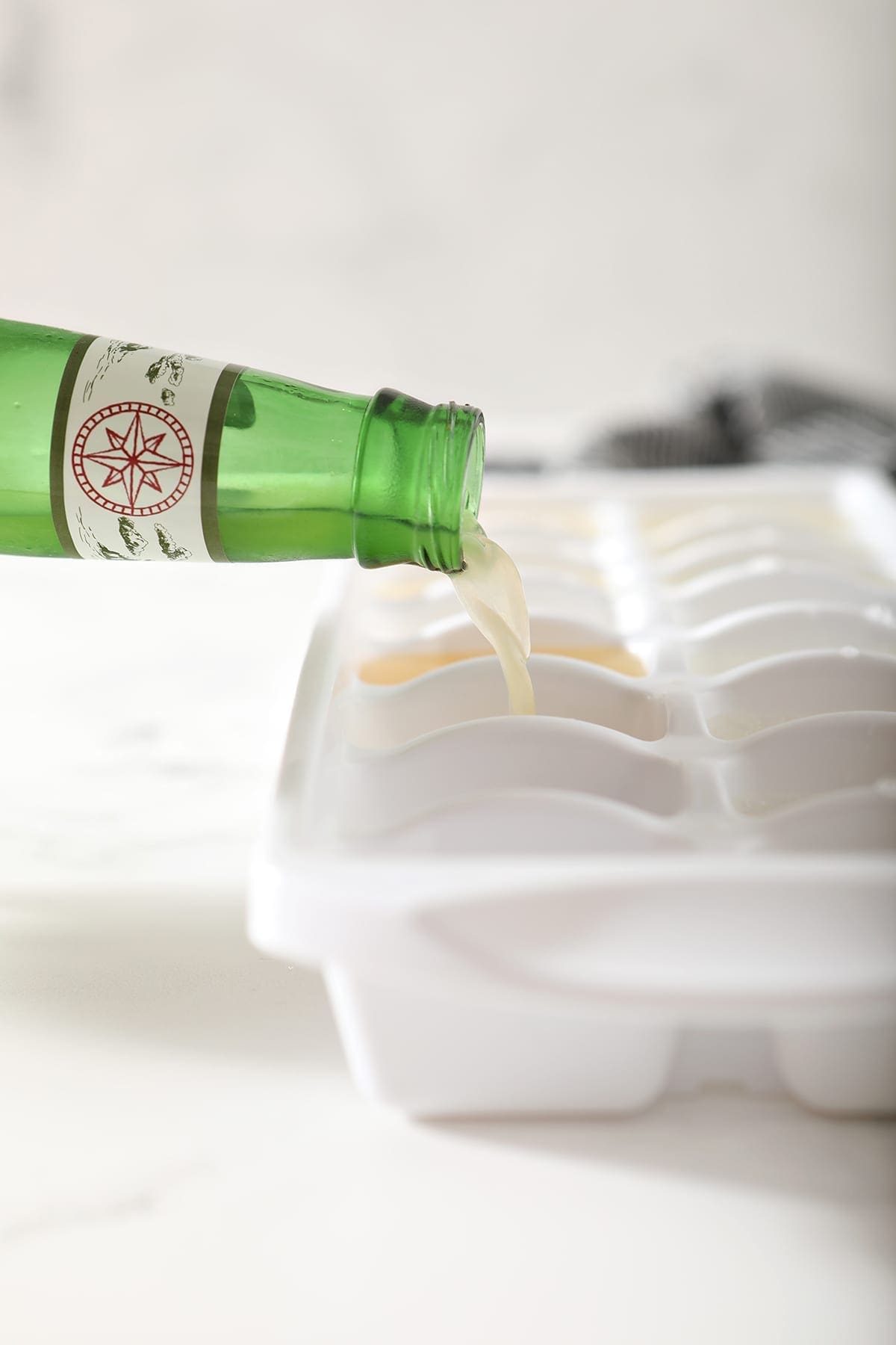 Ginger beer pours into a white ice cube tray