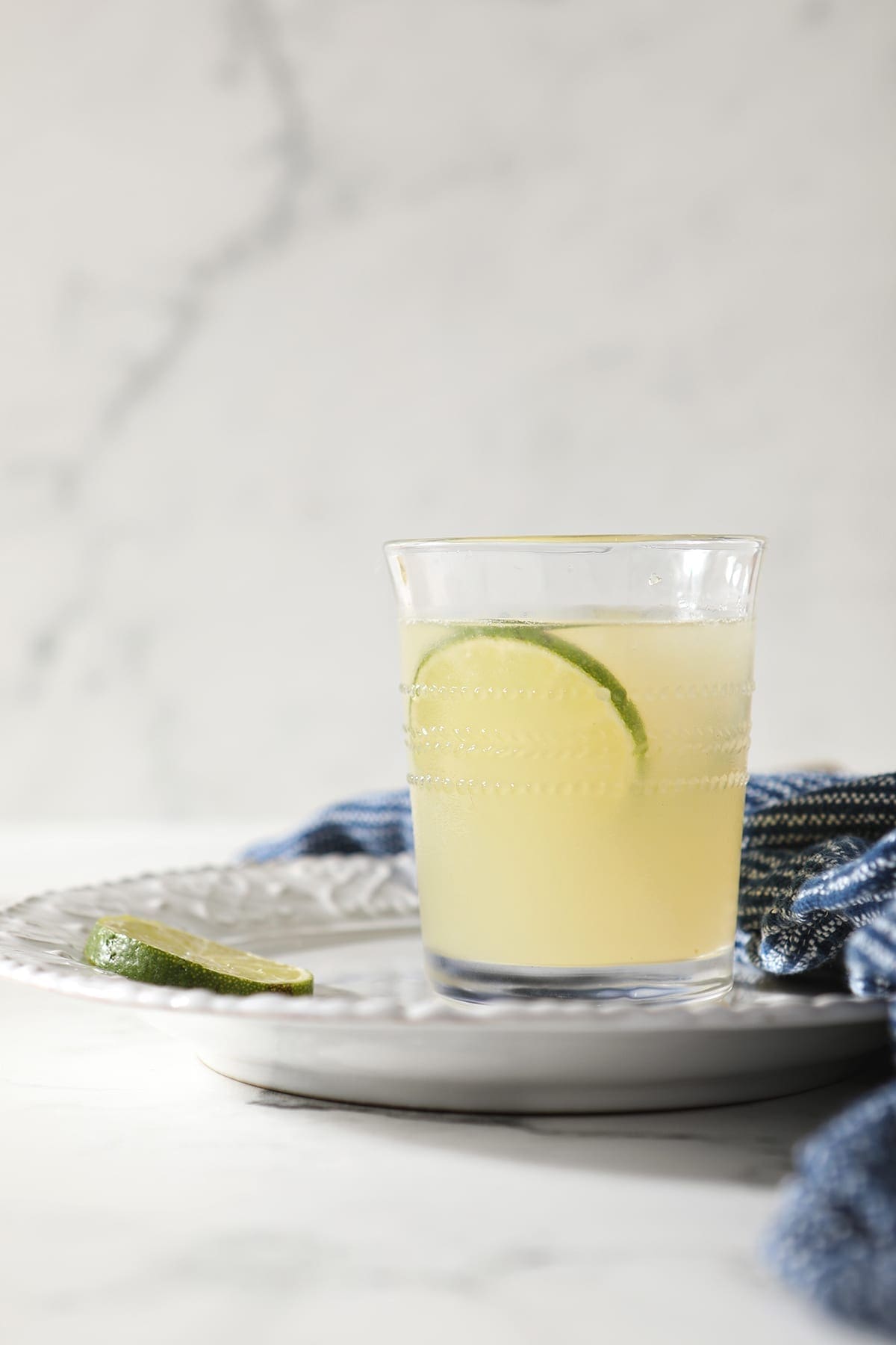 A Frozen Moscow Mule sits on a white plate on marble with slices of lime for garnish