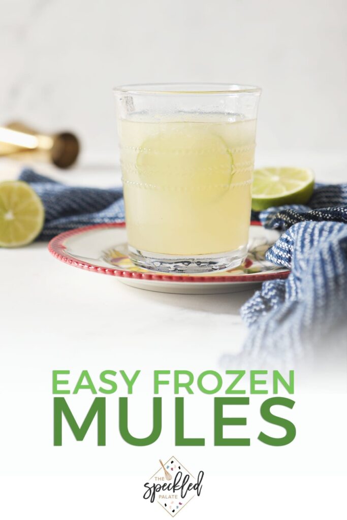 A glass of a Frozen Mule garnished with a lime round sits on a red-rimmed plate by a blue towel on marble with the text "Easy Frozen Mules"