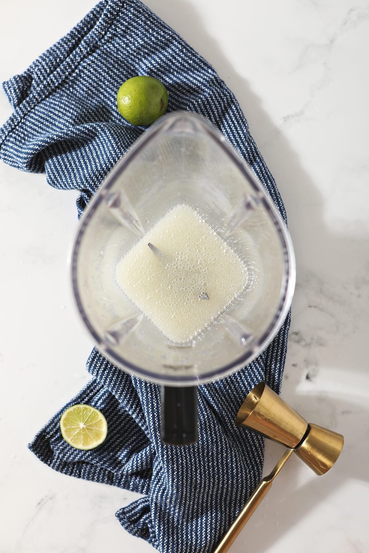 A Frozen Moscow Mule just blended inside a blender, sitting on top of a blue towel on marble