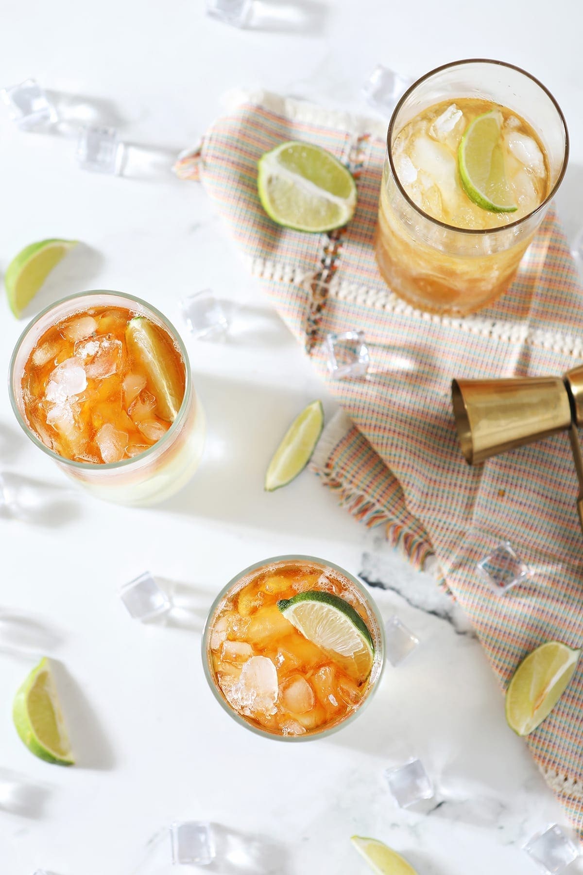 Overhead of three Rum Moscow Mules on marble, surrounded by lime wedges and ice cubes