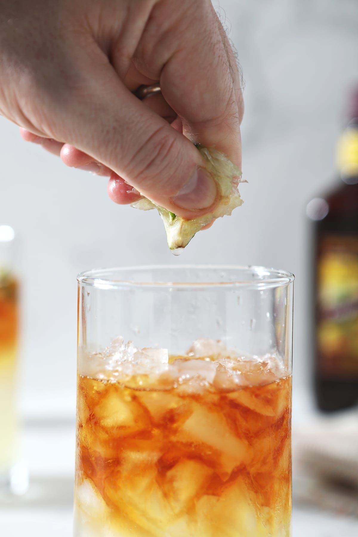 A lime wedge is squeezed into a highball glass over a brown liquid