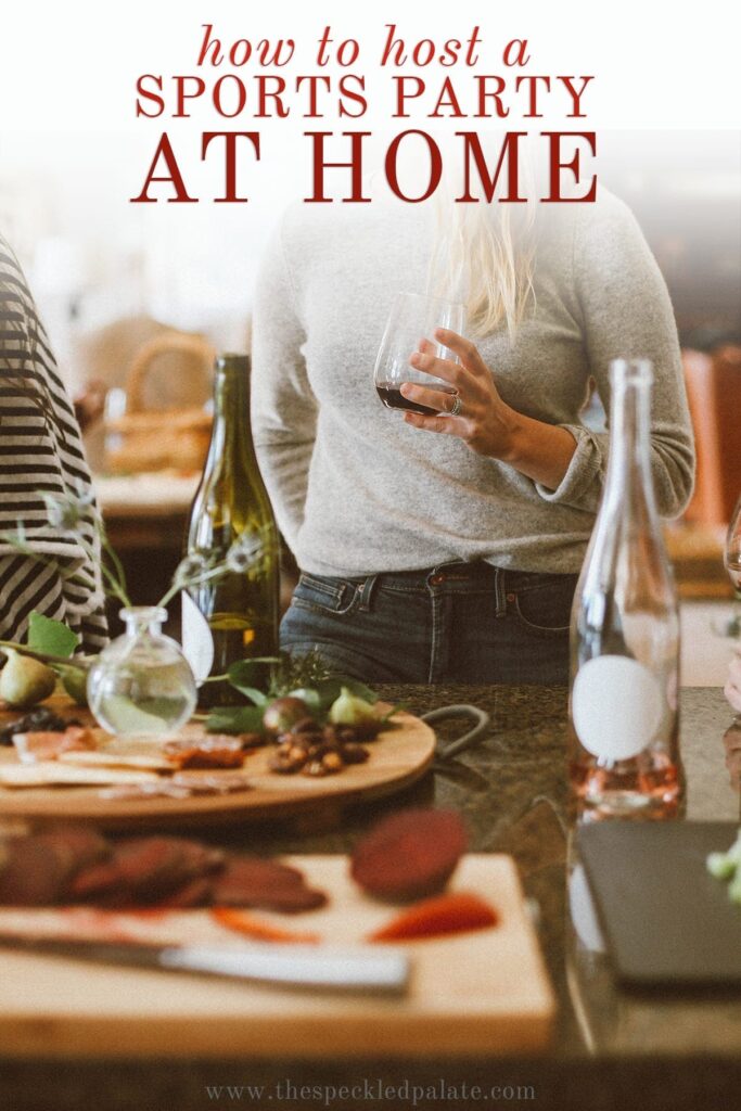 Women holding wine glasses stand by charcuterie and cheese boards with the text 'how to host a sports party at home'