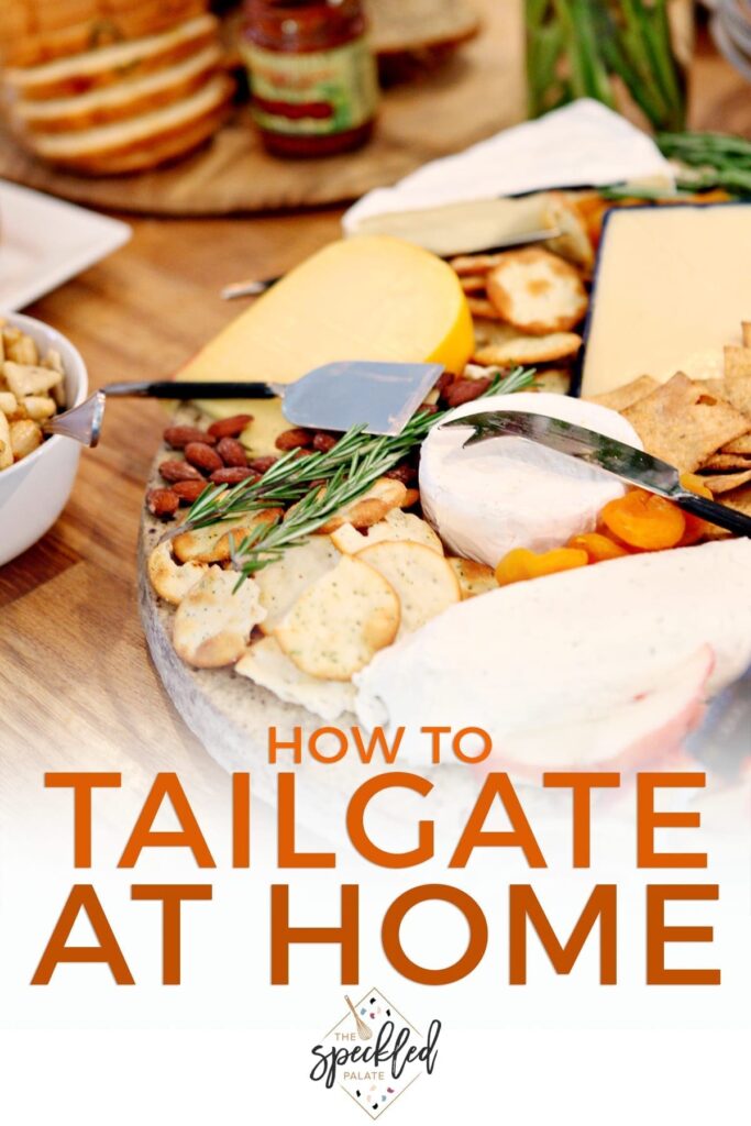 A cheese tray on a table with food at a potluck party with the text 'how to tailgate at home'