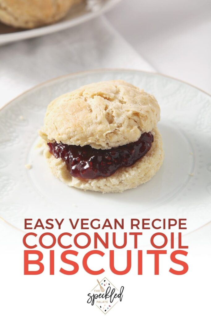 A biscuit with raspberry jam on a white plate with other biscuits and jam in the background with the text 'easy vegan recipe coconut oil biscuits'