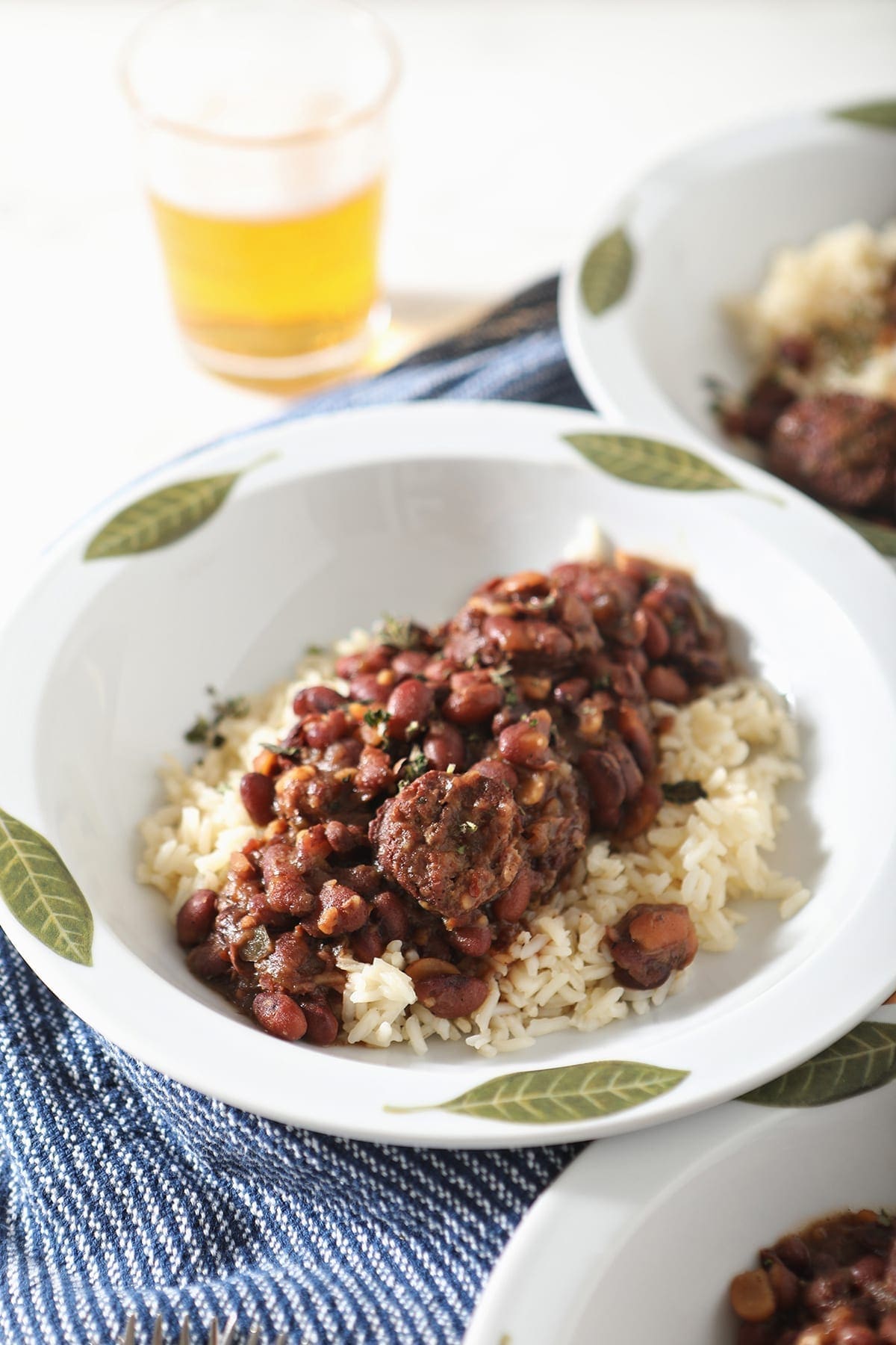 Close up of Red Beans served over white rice in a white bowl on a blue striped towel