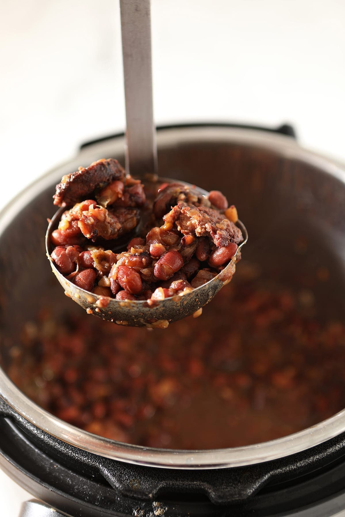 A ladle lifts red beans out of the Instant Pot, after cooking