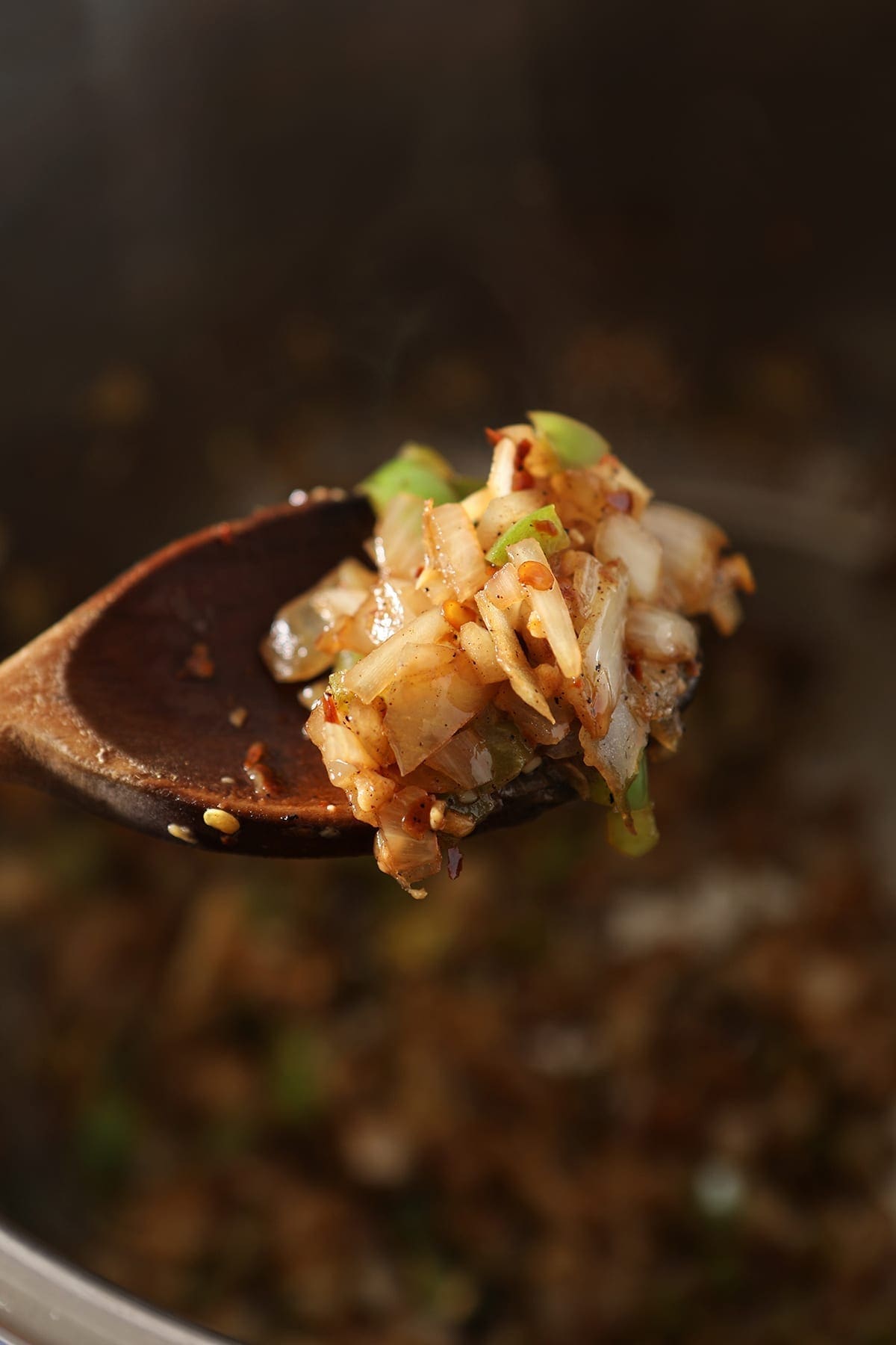 A wooden spoon holds sauteed veggies