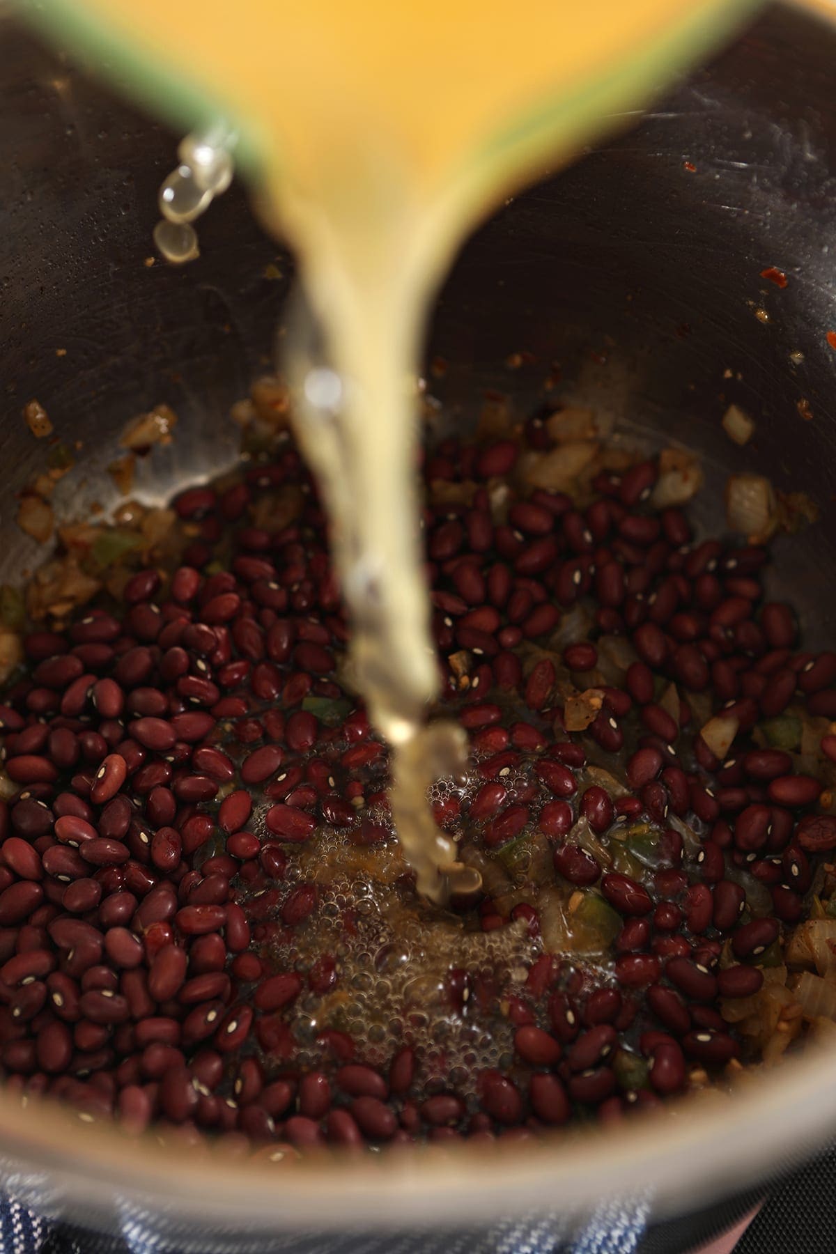 Chicken stock is poured into the pot on top of other ingredients