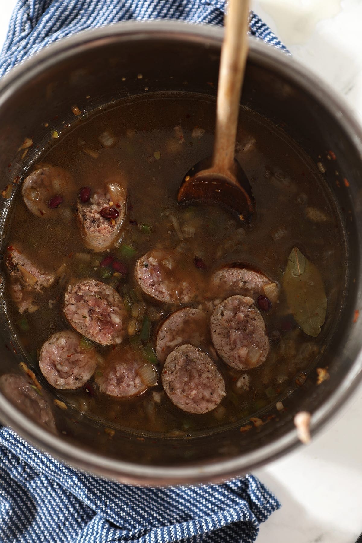 Sausage and other ingredients are stirred before the Instant Pot lid is placed, and the ingredients cook on high pressure