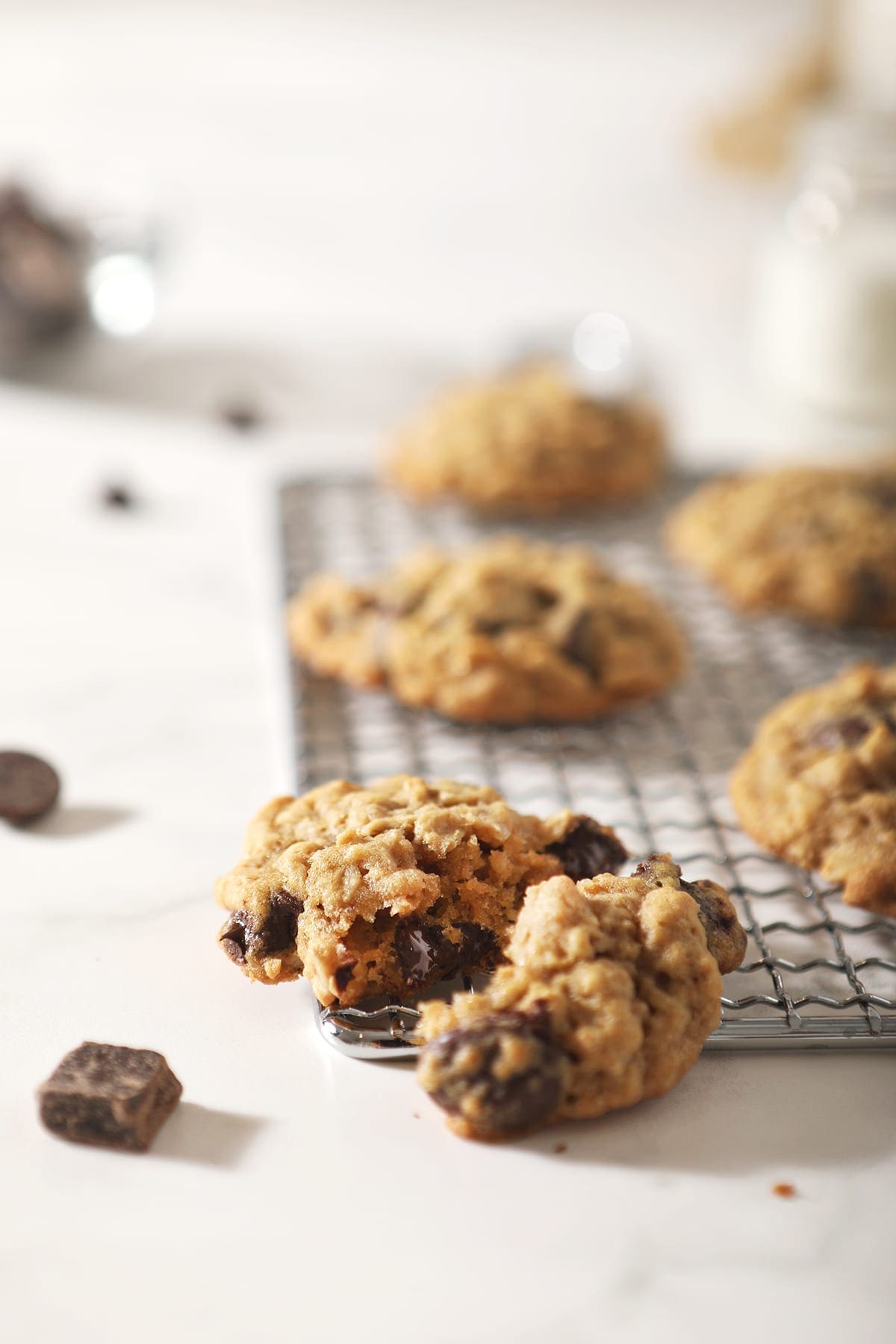 A halved oatmeal chocolate chip cookie on a wire cooling rack with other cookies behind it