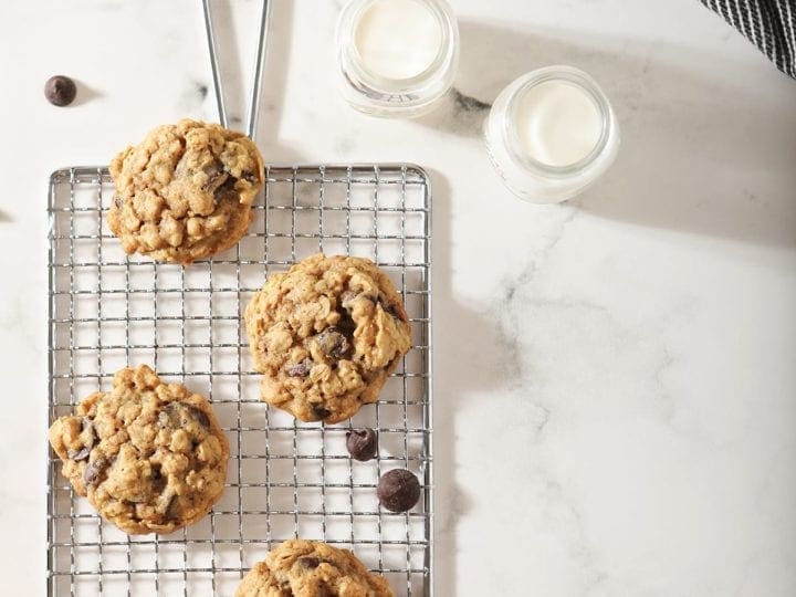 Several cookies on a wire cooling rack with milk around them