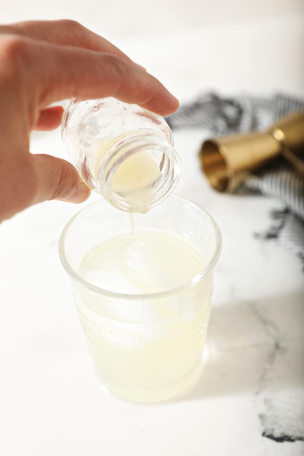 A hand pours lime juice into a ginger beer and vodka cocktail