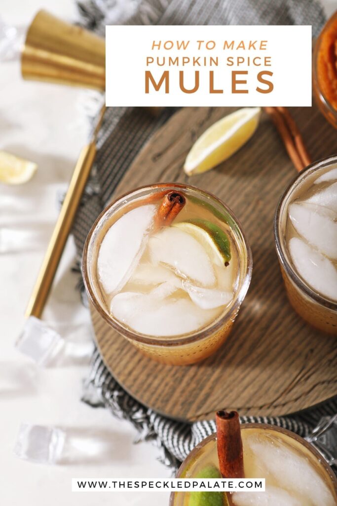 Overhead of three Pumpkin Spice Moscow Mules on a wooden serving dish next to to limes, a jigger and a bowl of pumpkin puree with the text 'how to make pumpkin spice mules'