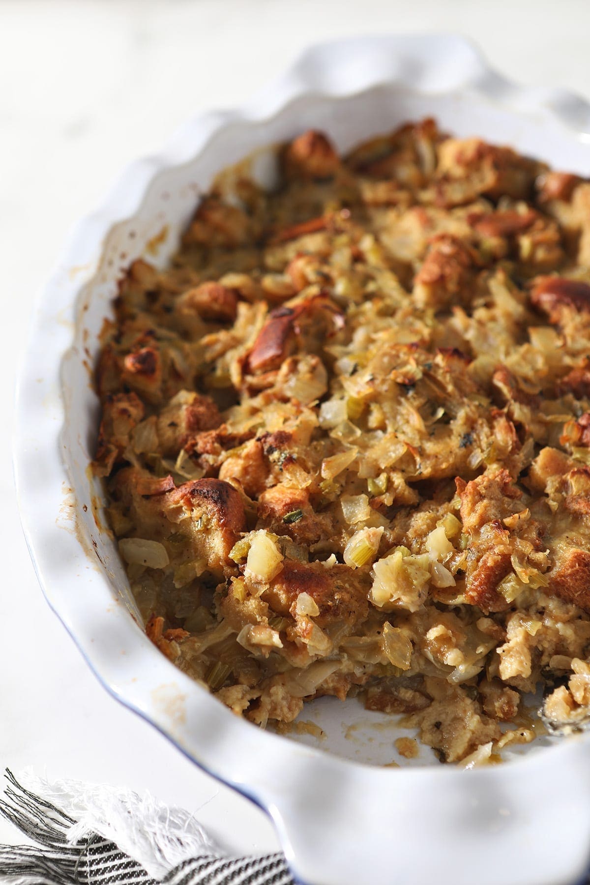 Close up of a casserole dish holding a classic bread stuffing recipe with a scoop taken out of it