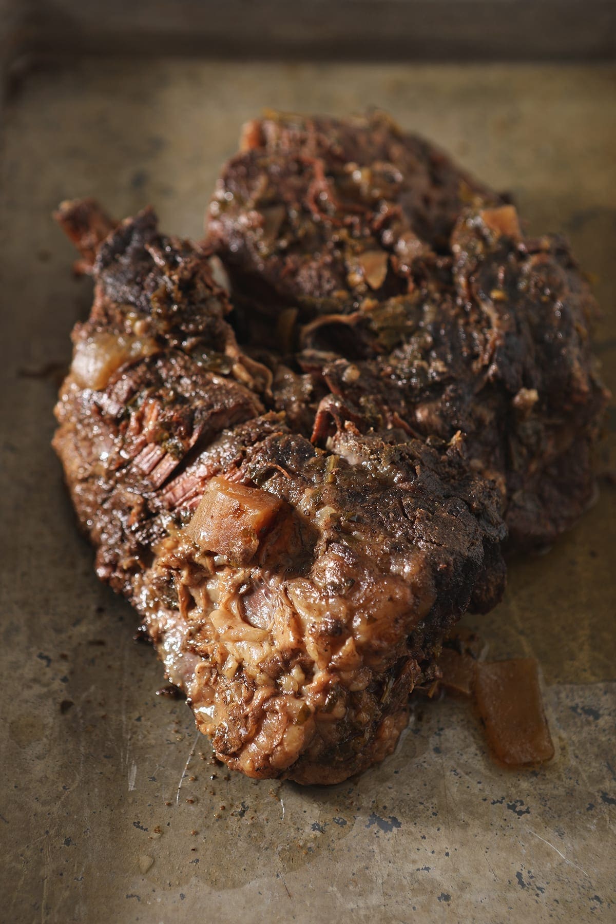 A slow cooker roast on a baking sheet before shredding