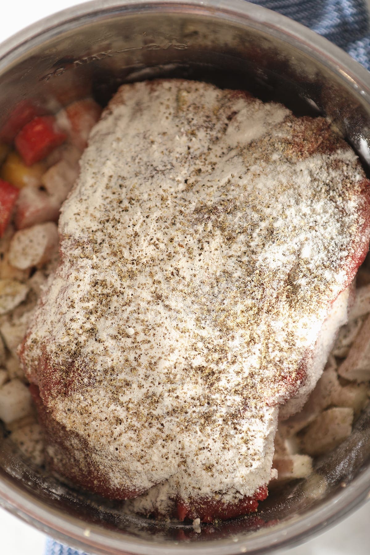 Close up of a roast in a slow cooker after seasonings were added