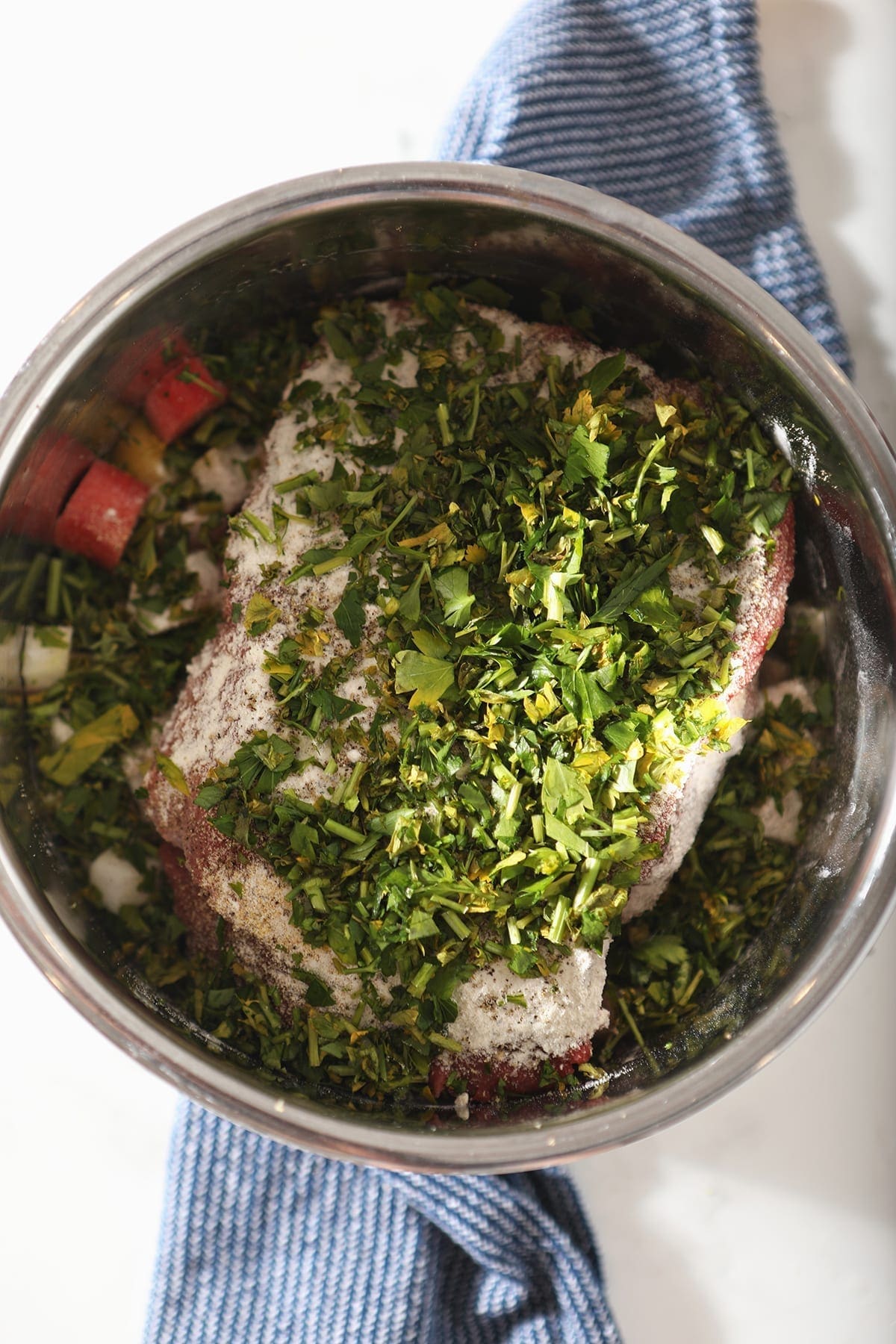 Overhead of a beef roast with veggies, parsley and spices added before cooking