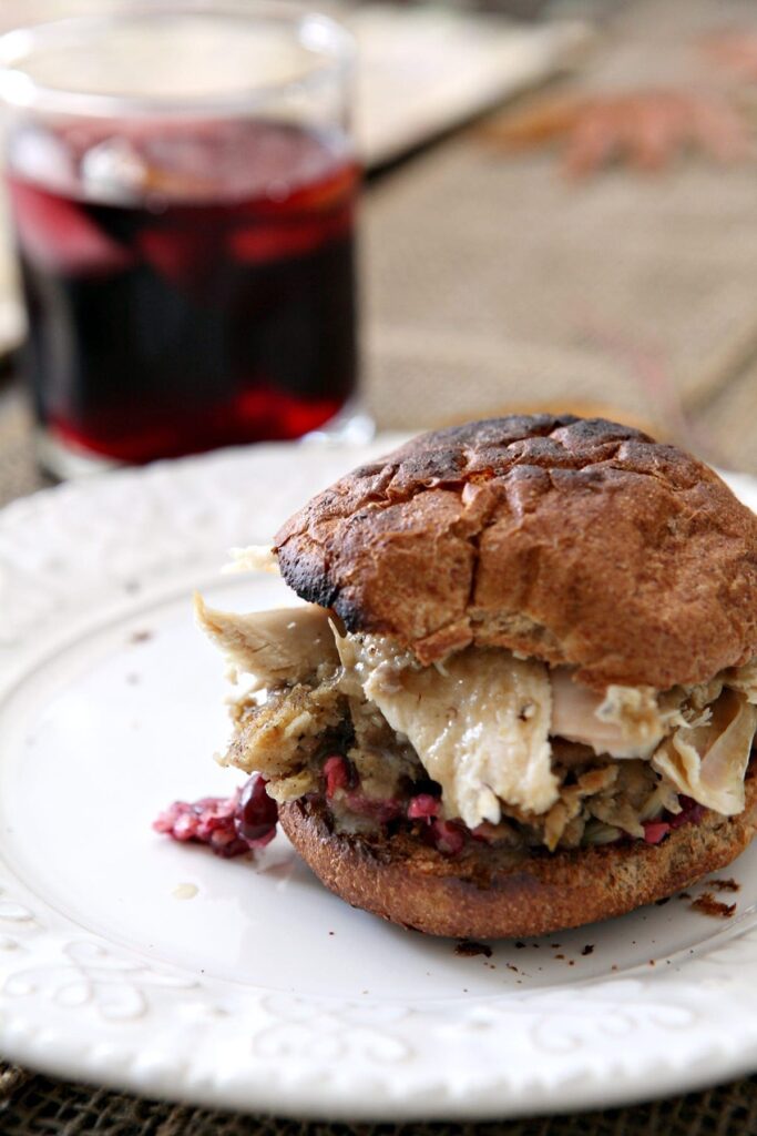 A Turkey Cranberry Sandwich on a toasted bun sits on a white plate