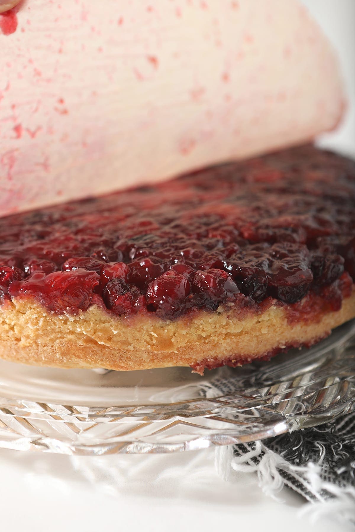 Parchment paper is peeled off of the cranberry sauce layer of the cake