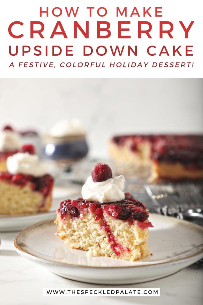 A slice of cranberry upside down cake garnished with a dollop of whipped cream and a cranberry on a white pottery plate with other slices behind it with the text 'how to make cranberry upside down cake. a festive, colorful holiday dessert!'