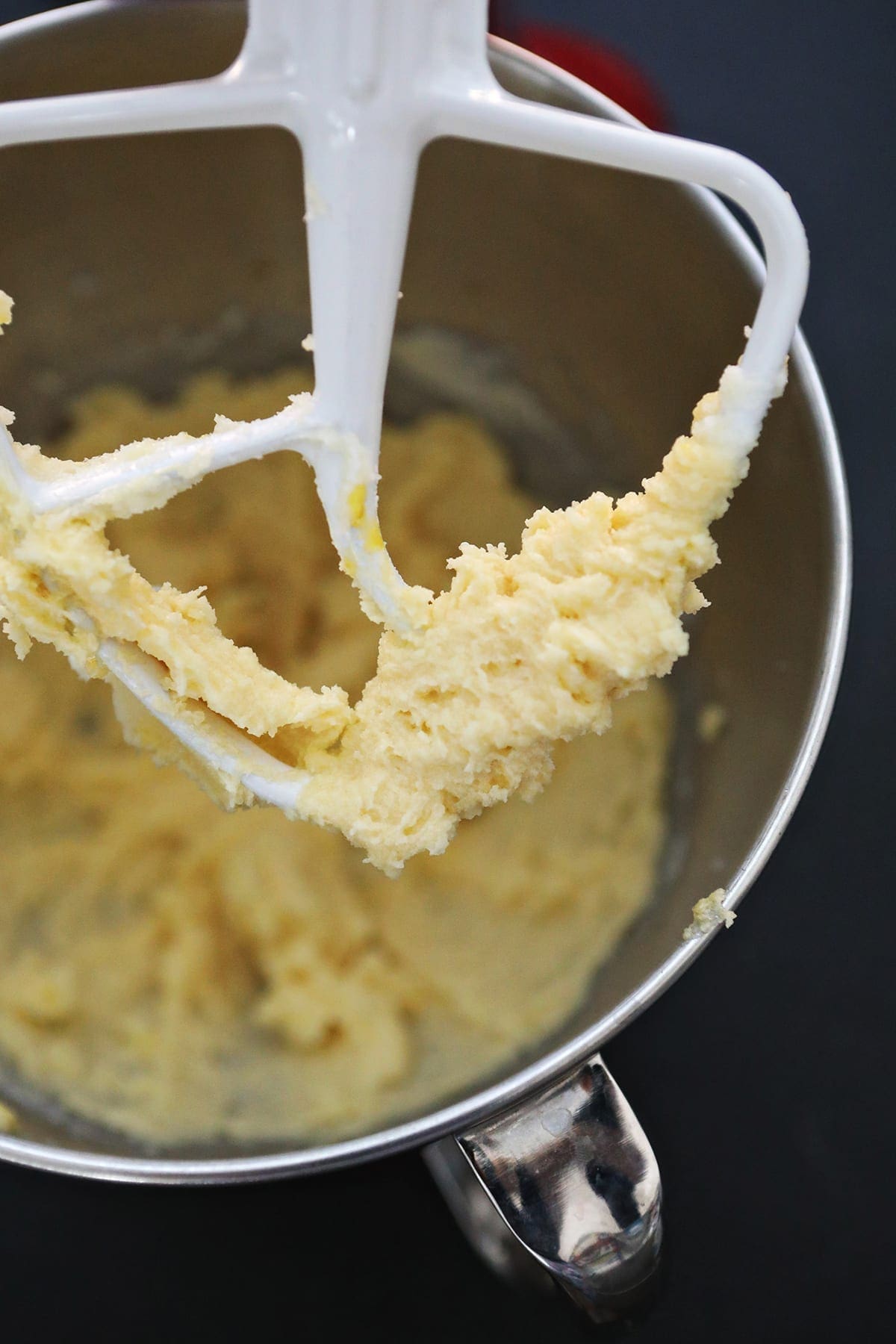 Close up of a stand mixer paddle after eggs and vanilla are whipped into the batter