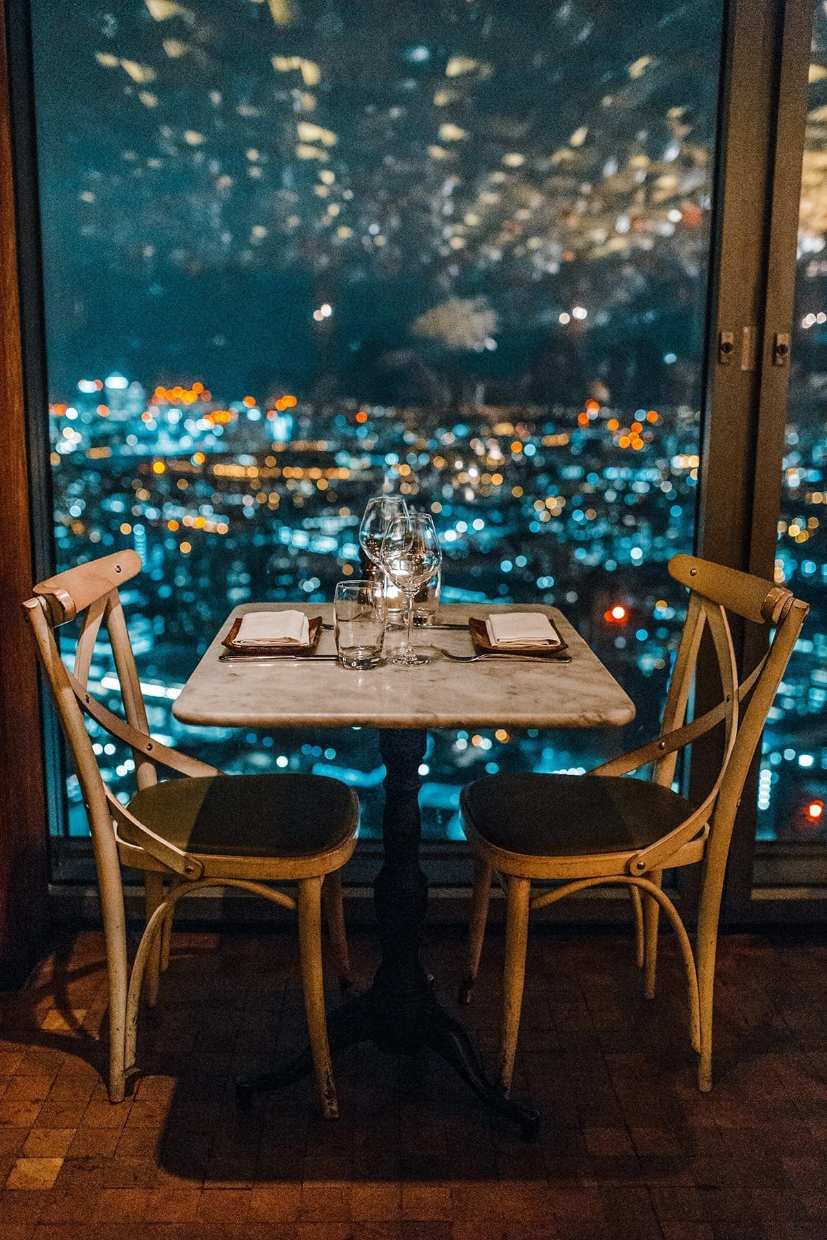 A table for two set next to a window with lights twinkling outside