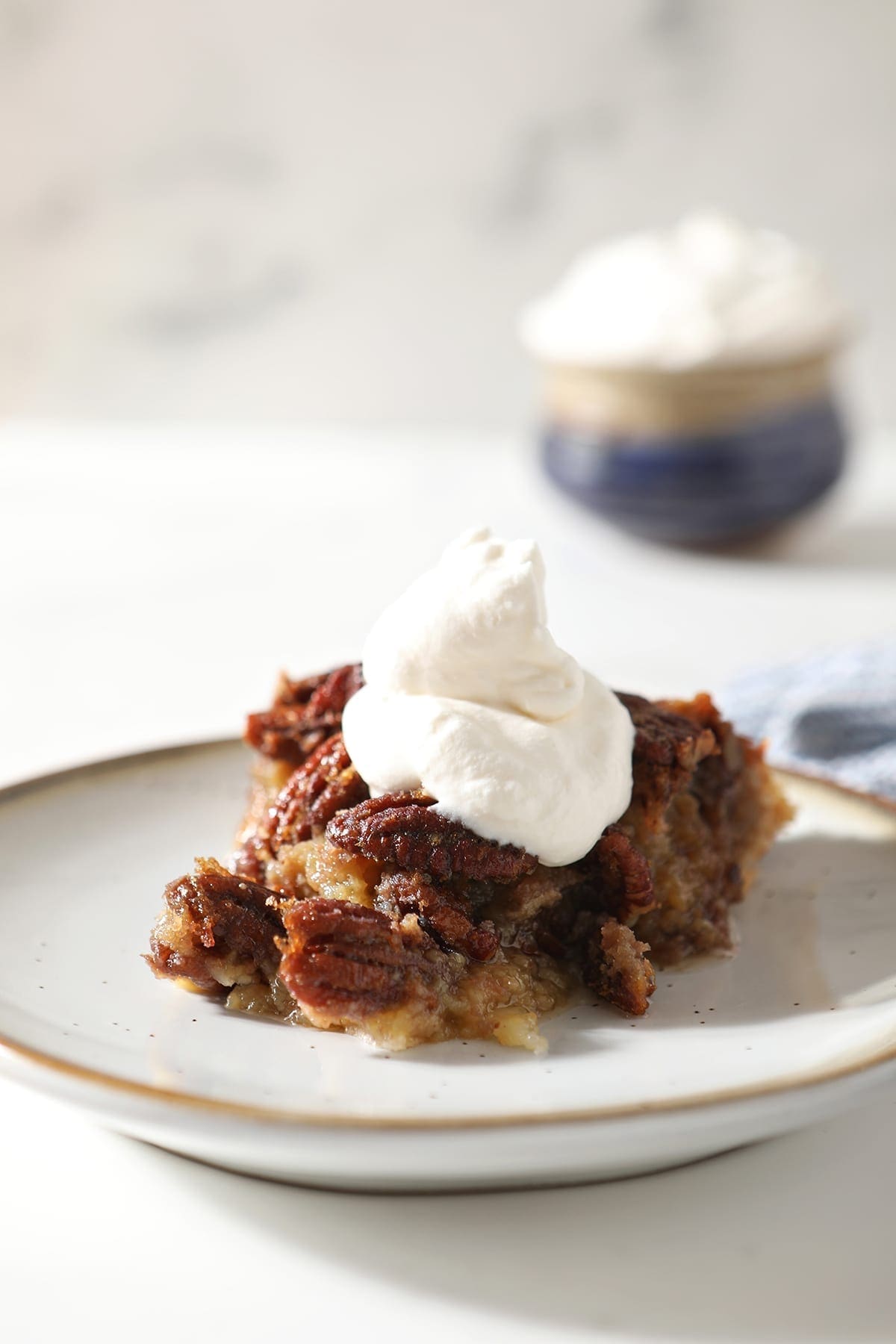 Close up of a slice of Bourbon Pecan Pie with whipped cream on top