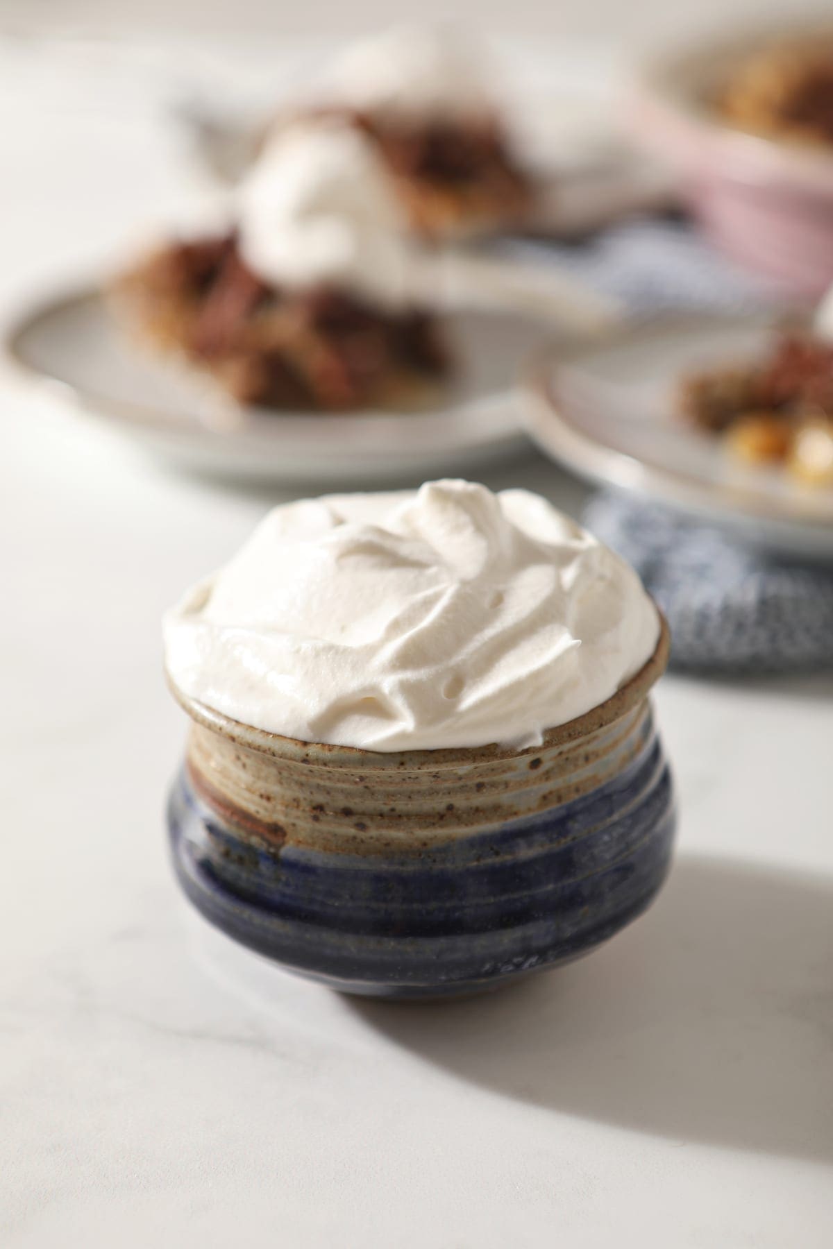 Close up of a blue pottery bowl holding a serving of homemade sweetened whipped cream