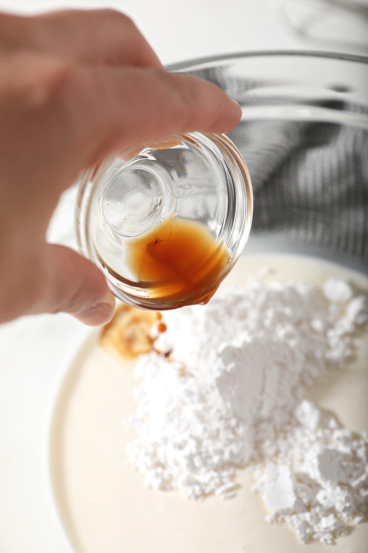 Vanilla is poured into a bowl with powdered sugar and heavy whipping ream